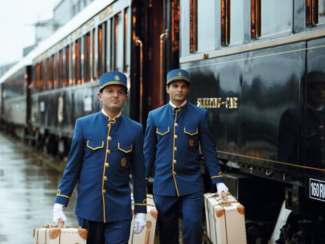 Venice Simplon-Orient-Express am Bahnsteig, zwei Stewards in blauen Uniformen tragen das Gepäck | © Belmond