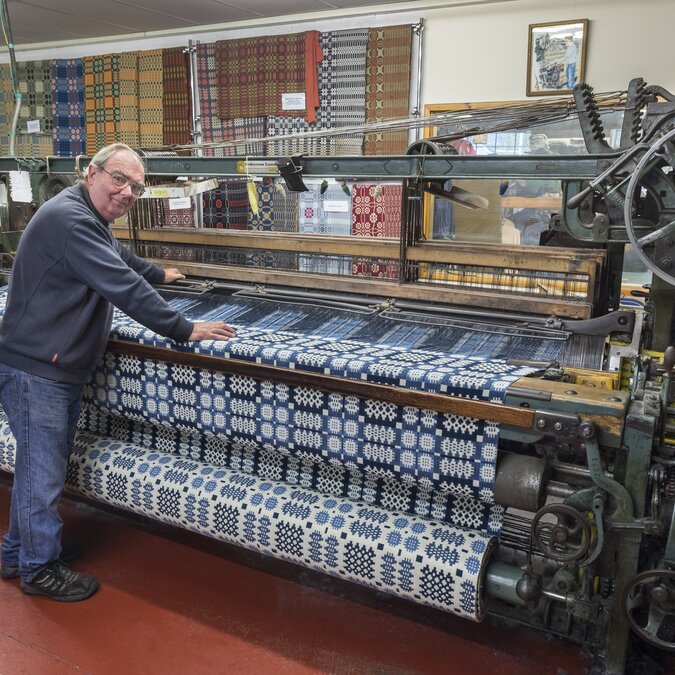 Historischer Webstuhl in traditioneller Manufaktur mit kunstvoll gemustertem Stoff und klassischer Technik der Textilherstellung. | © Crown Copyright (2026) Welsh Government