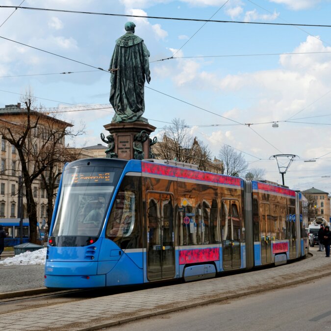 Szenerie einer Strassenbahn, die an einem sonnigen Wintertag an einer schönen Strassenecke in München vor der Statue von König Maximalian hält | © Shutterstock 1559941772