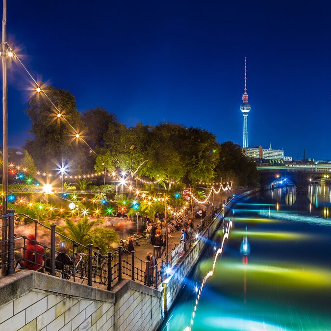 Leute tanzen auf Sommer Strandbar Beach Party nahe Spree Fluss auf der historischen Museumsinsel mit berühmtem Fernsehturm im Hintergrund während der blauen Stunde in der Nacht, Berlin Mitte Bezirk, Deutschland | © Shutterstock 377514604