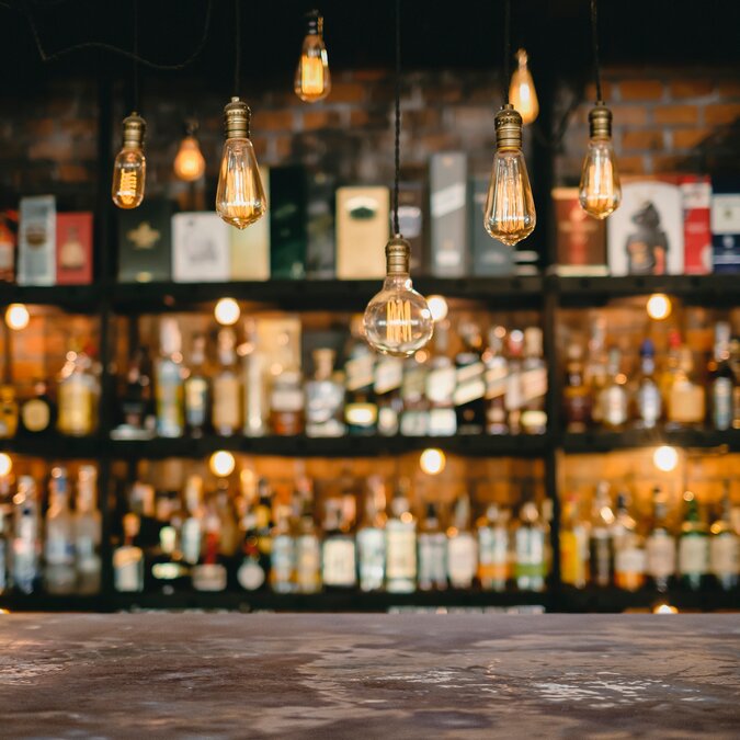 Metalltisch- und Vintage-Lampen mit Likörbarhintergrund | © Shutterstock 1671936808