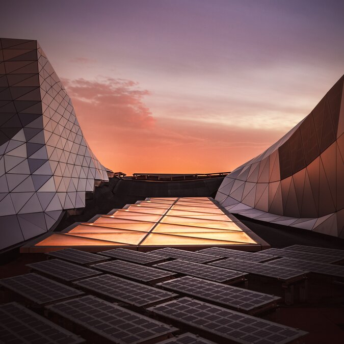 Detail des Confluence Museums in Lyon mit seinem einzigartigen architektonischen Stil und modernen Stahl- und Glasmaterialien. Fotovoltaik-Modelle und orangefarbenes Licht über Ökologie, Warnung, Elektrizität, Evolution. | © Shutterstock 1559528492