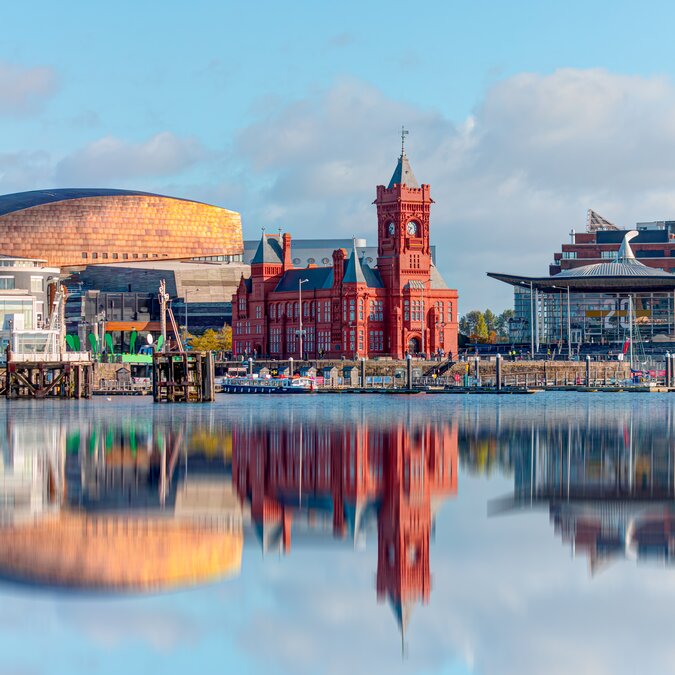 Cardiff Bay mit Wales Millennium Centre, Pierhead Building und moderner Uferpromenade, spiegelndes Wasser und markante Architektur bei klarem Himmel. | © shutterstock 1843969261