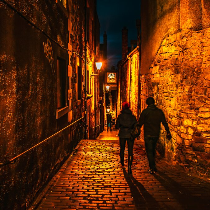 Zwei Personen laufen durch eine dunkle Gasse | © shutterstock / 1275916531
